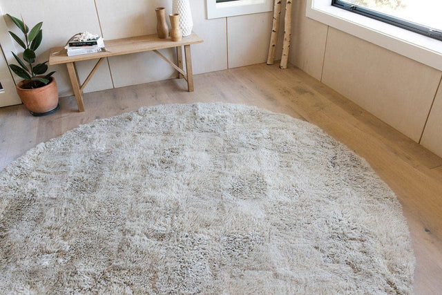 Natural coloured round shaped sheepskin wool floor rug in a minimalist interior